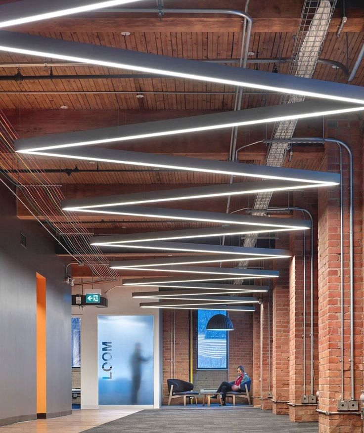 Open office with long linear light fixtures under a brick ceiling